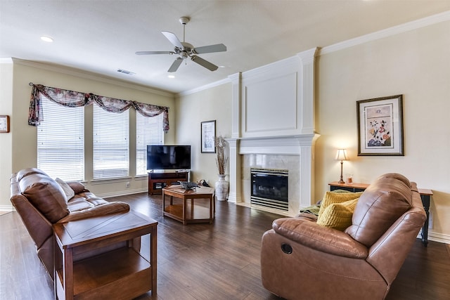 living room featuring a premium fireplace, ornamental molding, dark wood-type flooring, and ceiling fan