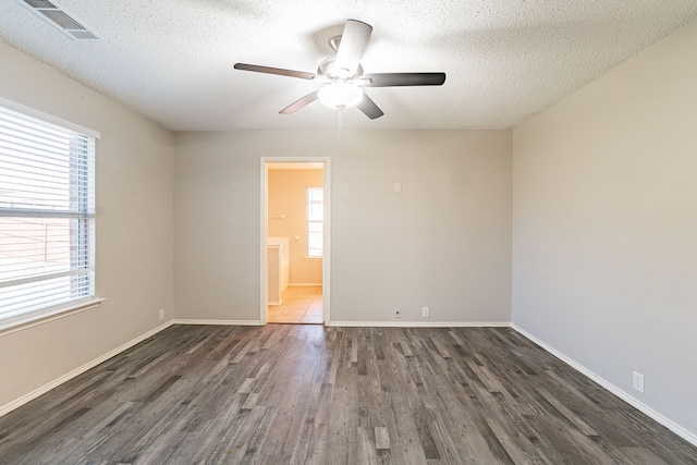 empty room featuring dark wood-type flooring, plenty of natural light, and a textured ceiling