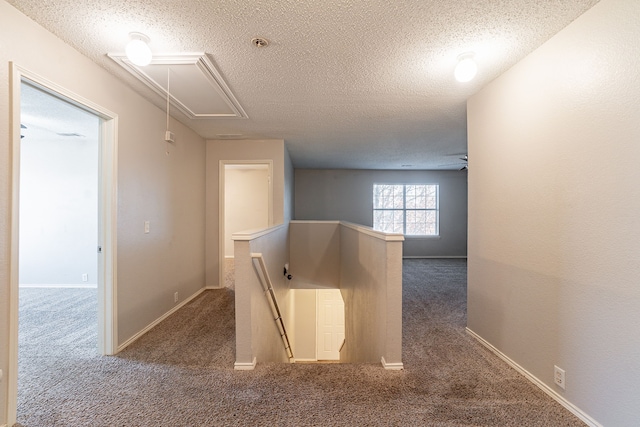 corridor with dark carpet and a textured ceiling