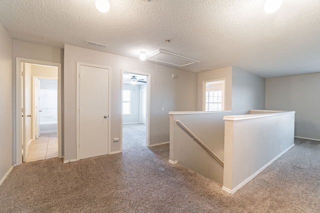 corridor with a textured ceiling and carpet