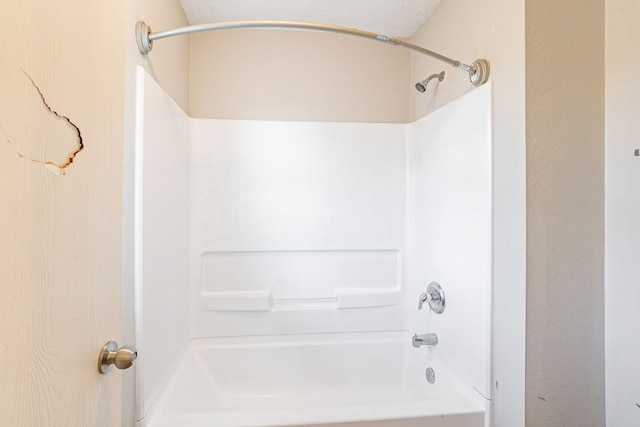 bathroom featuring bathtub / shower combination and a textured ceiling