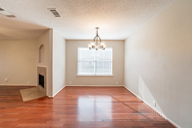 interior space featuring hardwood / wood-style flooring, a fireplace, a chandelier, and a textured ceiling