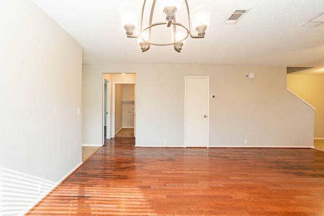 unfurnished room with hardwood / wood-style flooring, a notable chandelier, and a textured ceiling