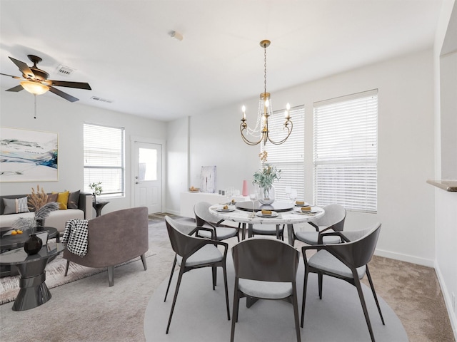 carpeted dining area featuring ceiling fan with notable chandelier