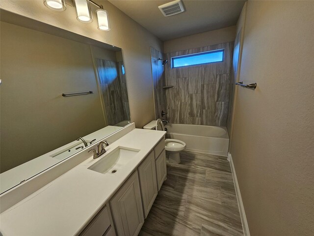 full bathroom featuring vanity, tiled shower / bath combo, and toilet