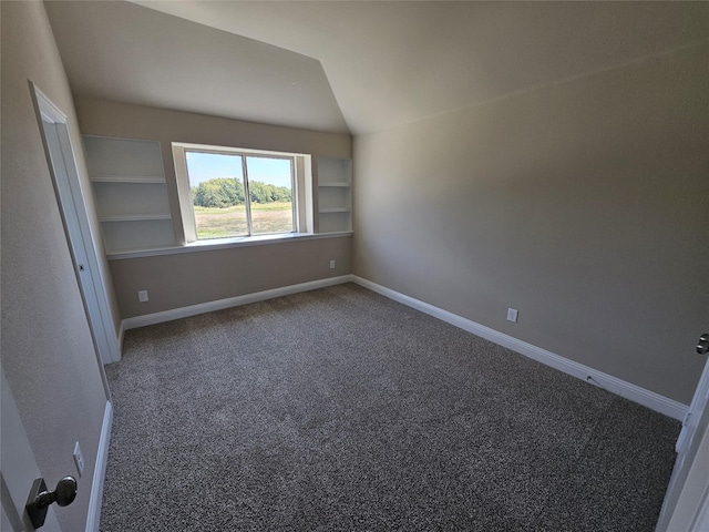 unfurnished room with carpet, built in shelves, and lofted ceiling