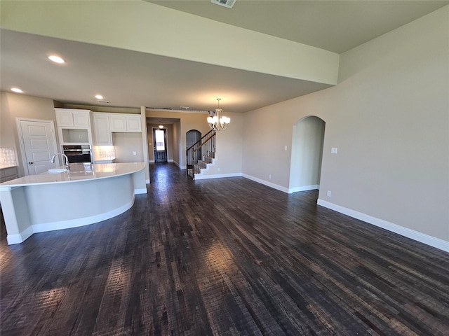 kitchen featuring stainless steel oven, an inviting chandelier, white cabinets, a spacious island, and dark hardwood / wood-style flooring