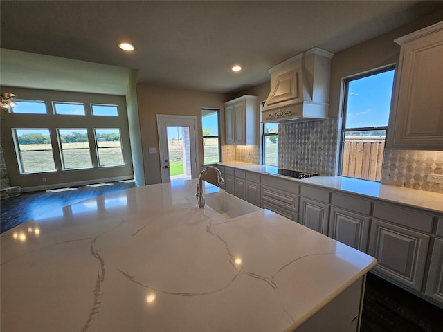 kitchen featuring light stone countertops, tasteful backsplash, custom exhaust hood, sink, and dark hardwood / wood-style floors