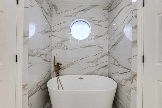 bathroom featuring a washtub and tile walls