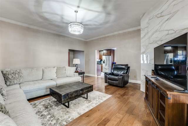 living room featuring ornamental molding, wood-type flooring, and an inviting chandelier