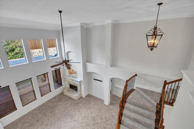 living room with ceiling fan with notable chandelier and crown molding