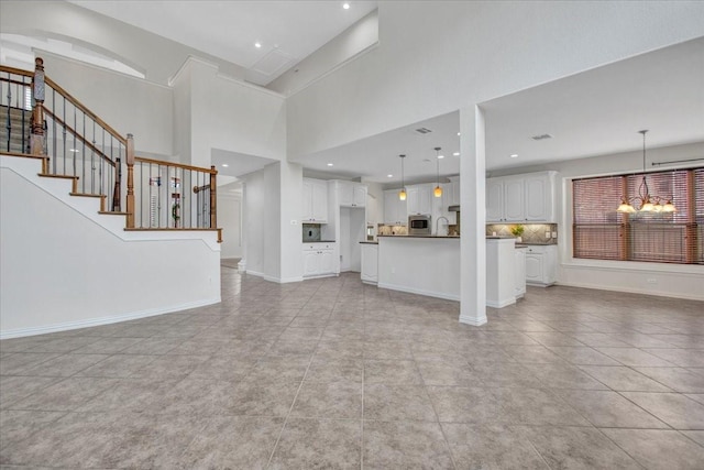 unfurnished living room featuring light tile patterned floors, a high ceiling, and a notable chandelier