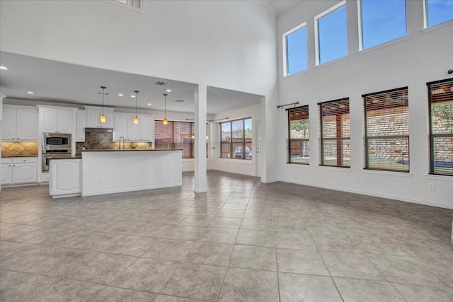 unfurnished living room featuring light tile patterned floors and a high ceiling