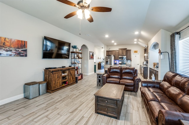 living room featuring ceiling fan, lofted ceiling, and light wood-type flooring