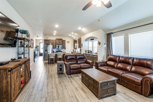 living room with ceiling fan, vaulted ceiling, and light hardwood / wood-style flooring