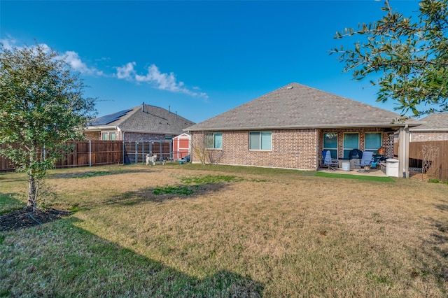 back of house featuring a storage shed, a yard, and a patio