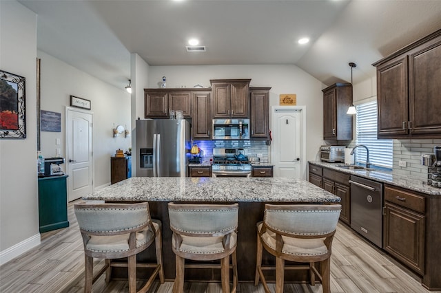 kitchen with stainless steel appliances, a kitchen island, hanging light fixtures, and sink