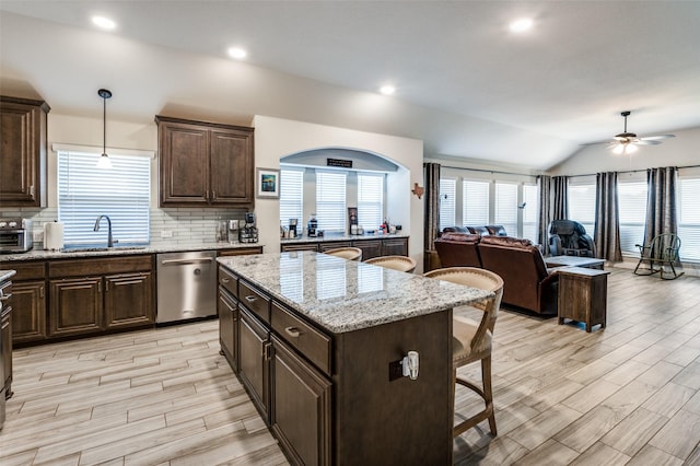 kitchen with sink, a breakfast bar, dishwasher, a center island, and decorative light fixtures