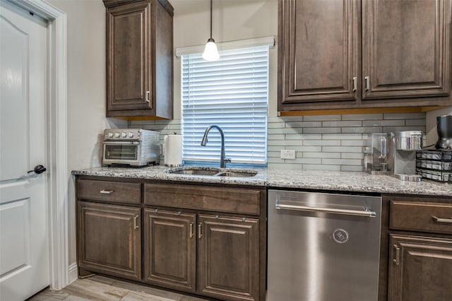 kitchen featuring sink, light stone counters, dark brown cabinets, stainless steel dishwasher, and decorative backsplash