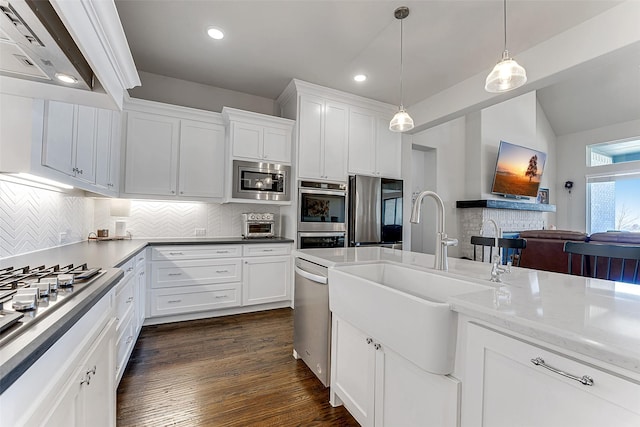 kitchen with appliances with stainless steel finishes, pendant lighting, white cabinets, backsplash, and sink