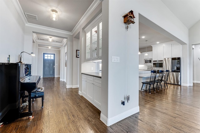 foyer with a healthy amount of sunlight, ornamental molding, and dark hardwood / wood-style floors