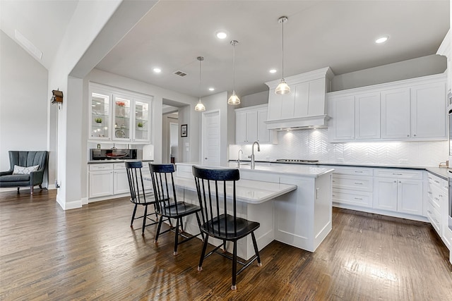 kitchen featuring a breakfast bar, white cabinetry, a kitchen island with sink, and pendant lighting