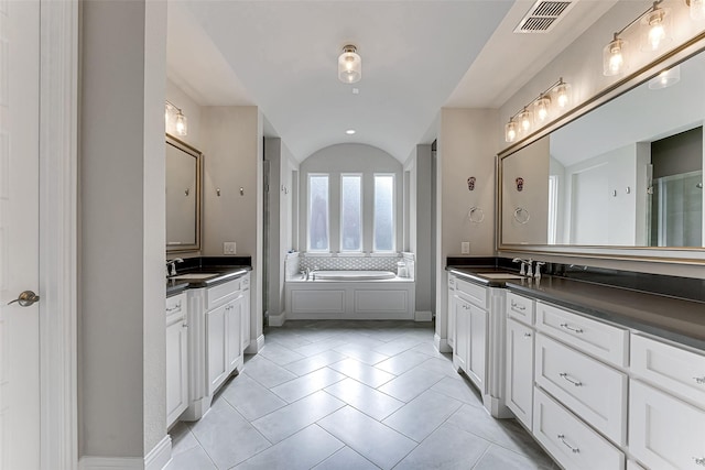 bathroom with lofted ceiling, a washtub, tile patterned flooring, and vanity