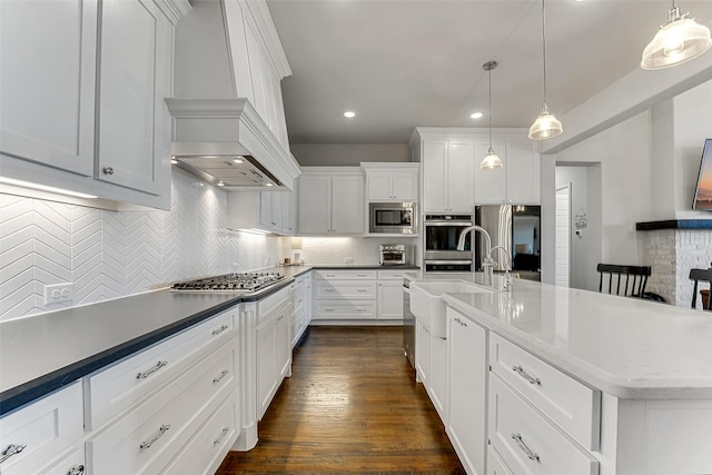 kitchen featuring stainless steel appliances, white cabinetry, backsplash, and hanging light fixtures