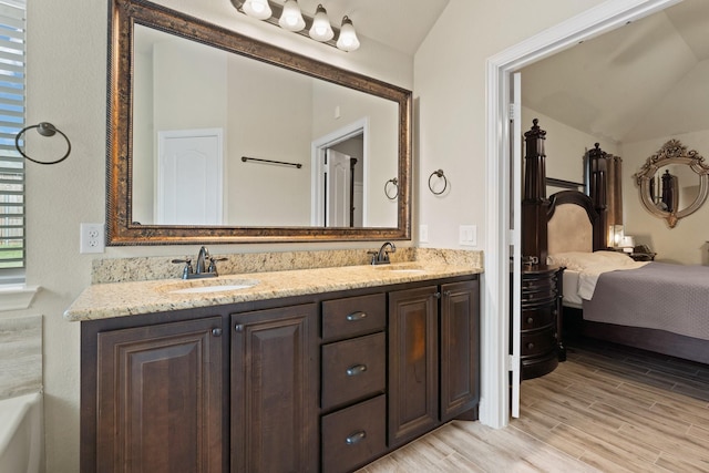 bathroom with vanity, hardwood / wood-style flooring, and vaulted ceiling