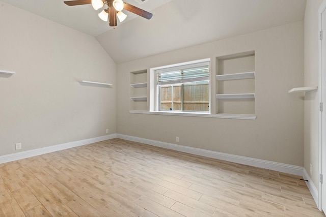 empty room with ceiling fan, lofted ceiling, built in features, and light wood-type flooring