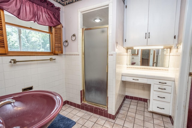 bathroom featuring tile patterned flooring, vanity, a shower with door, and tile walls