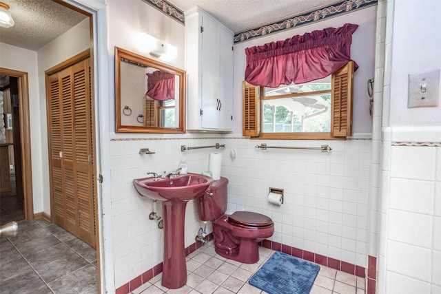 bathroom featuring tile patterned floors, a textured ceiling, and tile walls