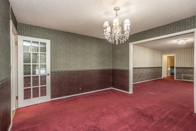 spare room with carpet flooring, a chandelier, and a textured ceiling