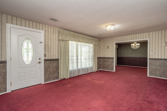 entryway featuring dark carpet and a textured ceiling