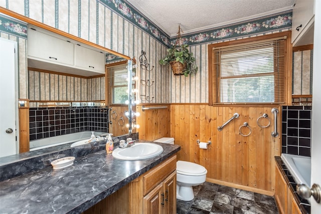 bathroom featuring vanity, wood walls, a bathing tub, toilet, and a textured ceiling