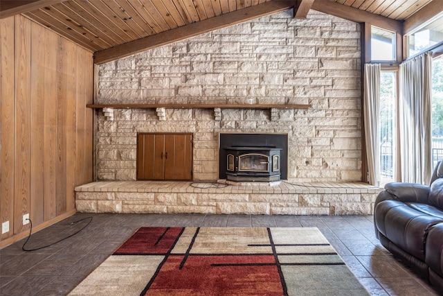 unfurnished living room featuring vaulted ceiling with beams, a wood stove, wooden walls, and wooden ceiling