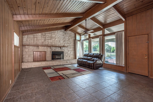 unfurnished living room with wood ceiling, ceiling fan, vaulted ceiling with beams, a wood stove, and wood walls