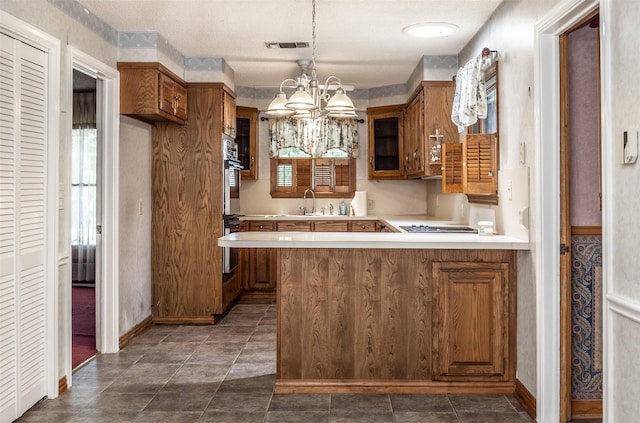 kitchen with pendant lighting, an inviting chandelier, sink, double oven, and kitchen peninsula