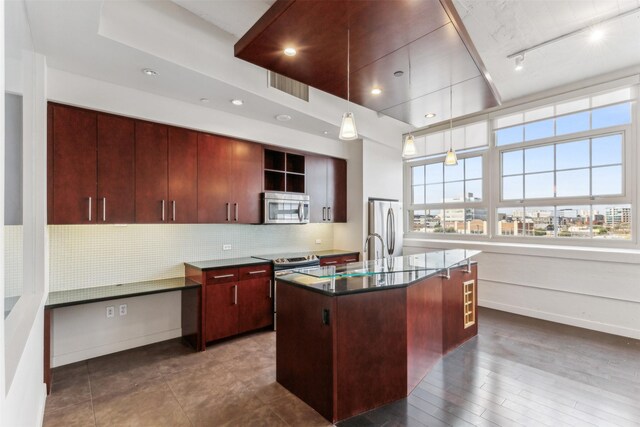 kitchen with pendant lighting, dark hardwood / wood-style floors, an island with sink, tasteful backsplash, and stainless steel appliances