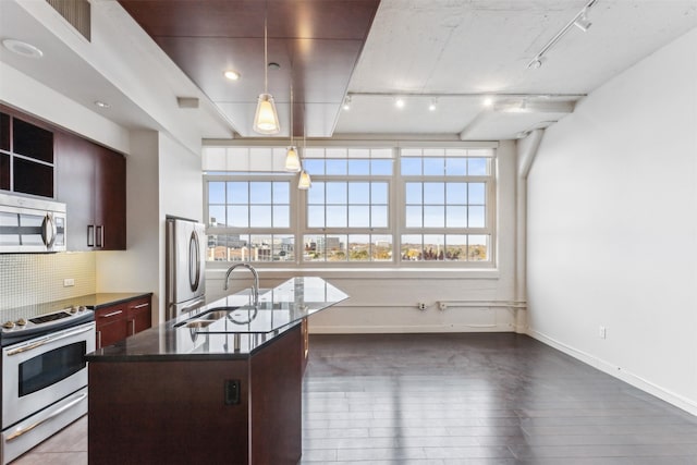 kitchen featuring sink, stainless steel appliances, backsplash, an island with sink, and track lighting