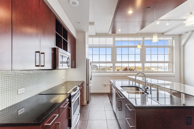 kitchen featuring appliances with stainless steel finishes, backsplash, a kitchen island with sink, sink, and light tile patterned flooring