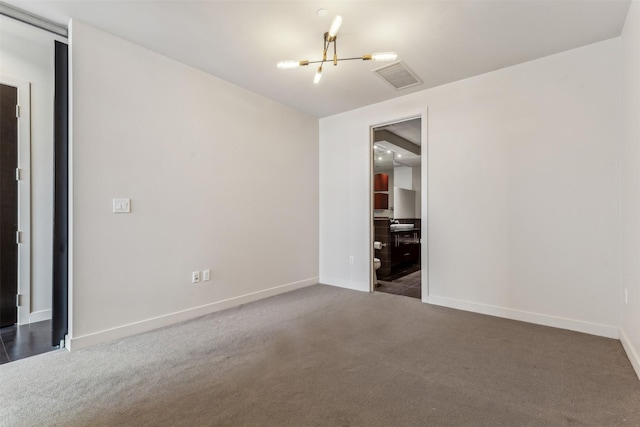 carpeted spare room with a notable chandelier