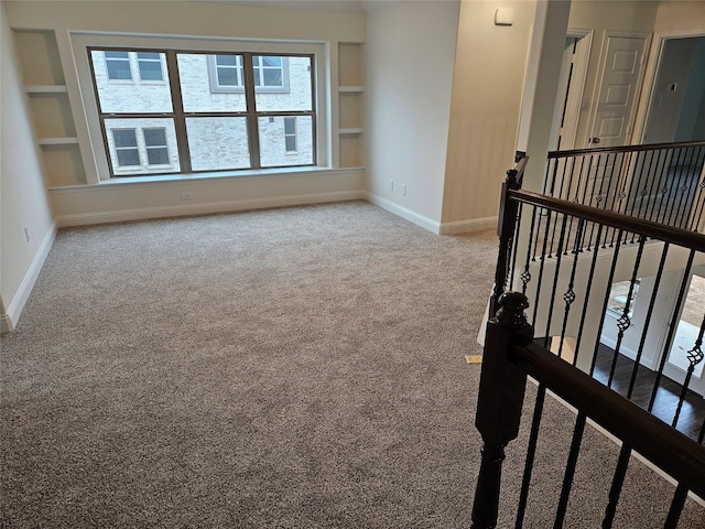 carpeted spare room featuring built in shelves