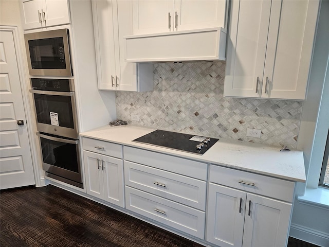 kitchen featuring black electric cooktop, backsplash, built in microwave, and white cabinets