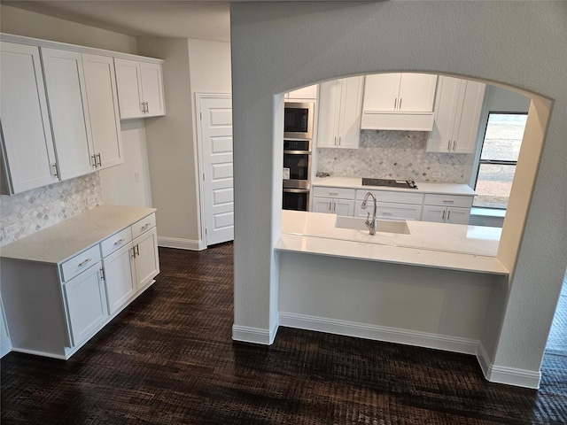 kitchen with tasteful backsplash, white cabinetry, built in microwave, sink, and black electric stovetop