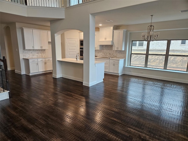 unfurnished living room featuring an inviting chandelier, a towering ceiling, sink, and dark wood-type flooring