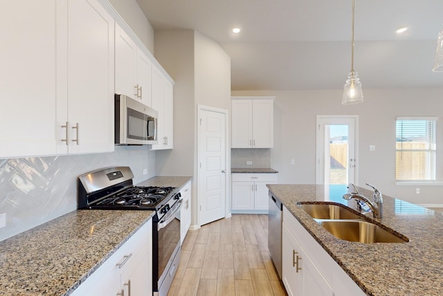 kitchen with stone counters, appliances with stainless steel finishes, white cabinetry, and sink