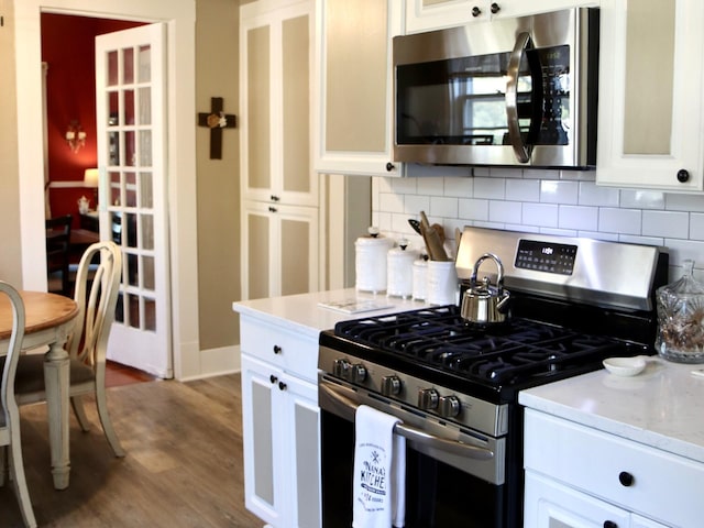 kitchen featuring white cabinetry, appliances with stainless steel finishes, hardwood / wood-style floors, and tasteful backsplash