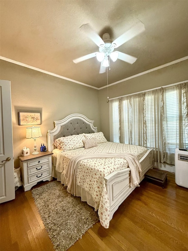 bedroom with ornamental molding, dark hardwood / wood-style floors, a textured ceiling, and ceiling fan