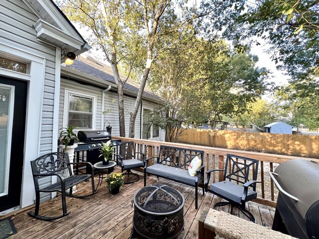 wooden deck with an outdoor fire pit and grilling area